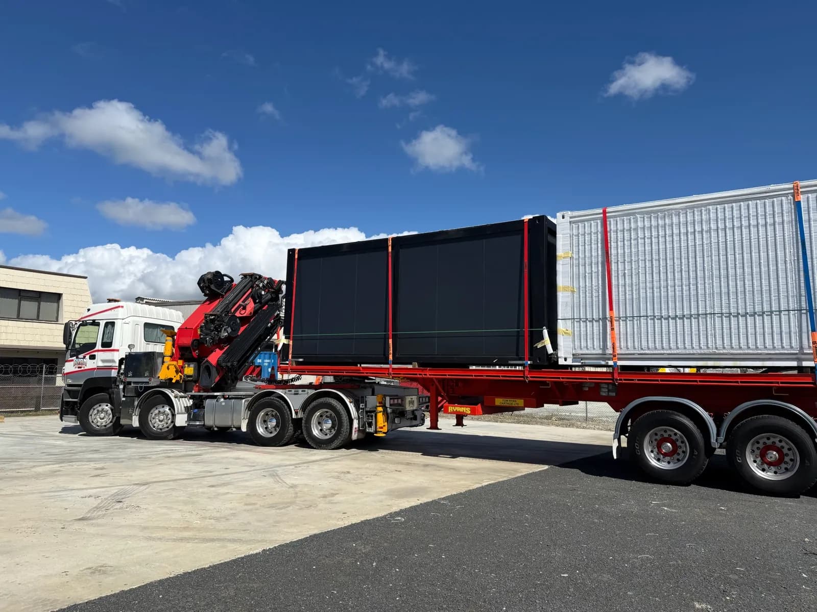 Truck with a mounted crane carrying two folded expandable homes on its trailer