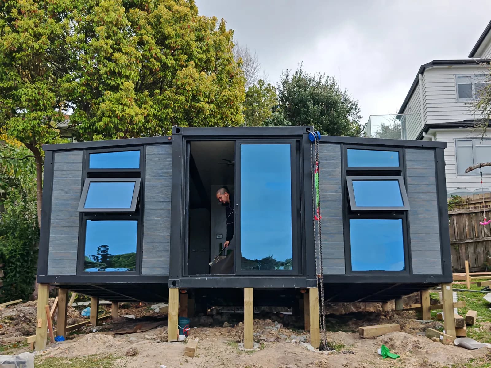 Grey Comfort 20 with both wings unfolded on timber piles, an installer in the doorway