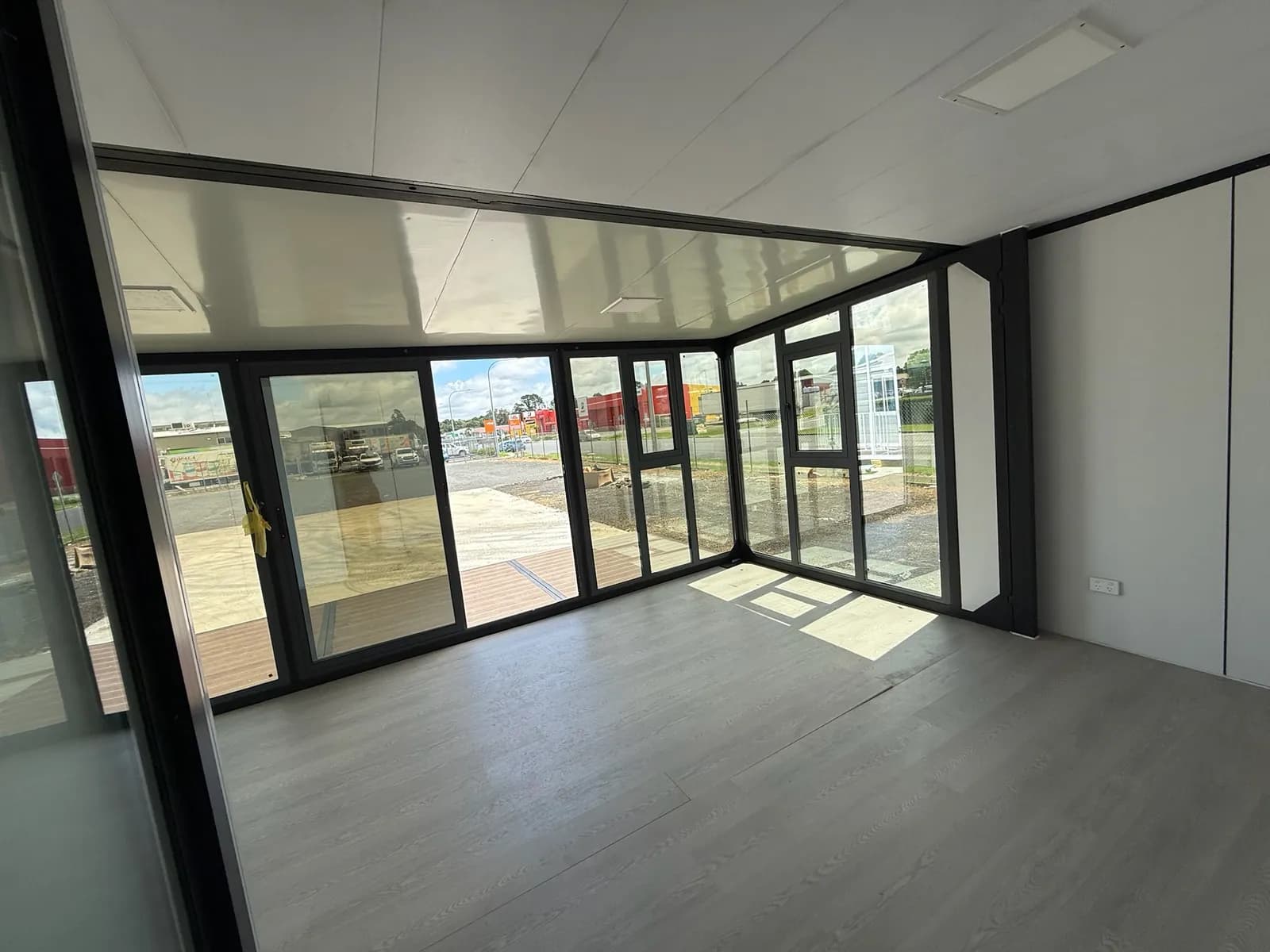 Open-plan interior with a grey floor and full-height windows on three sides