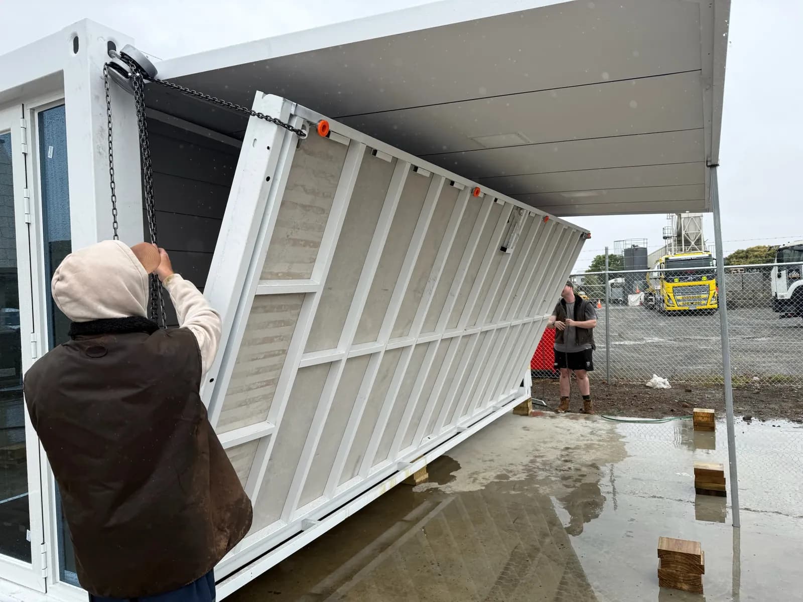 Installer lowering the folding wall panel of a white expandable home