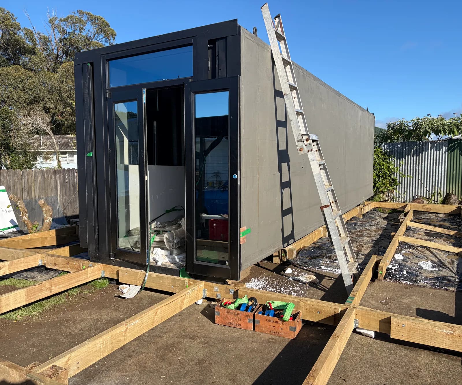 Folded black module set on a timber subframe, ready to unfold