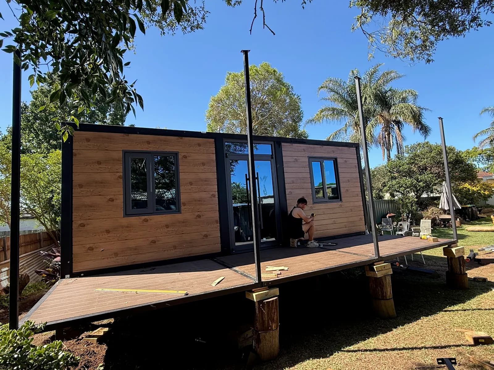 Expandable home with timber-look cladding on a raised deck, roof posts going up