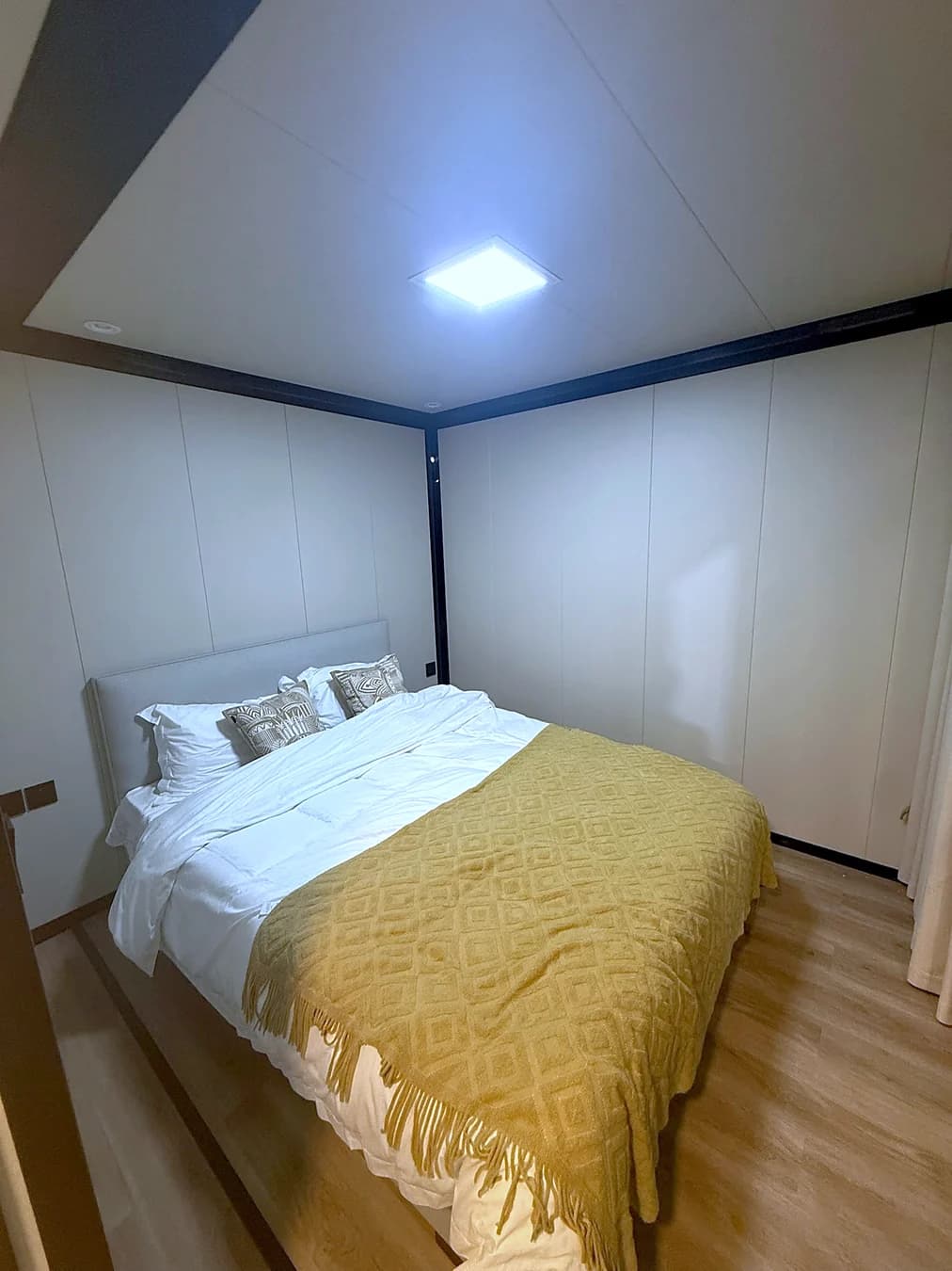 Bedroom with a made bed, panel walls and wood-look flooring
