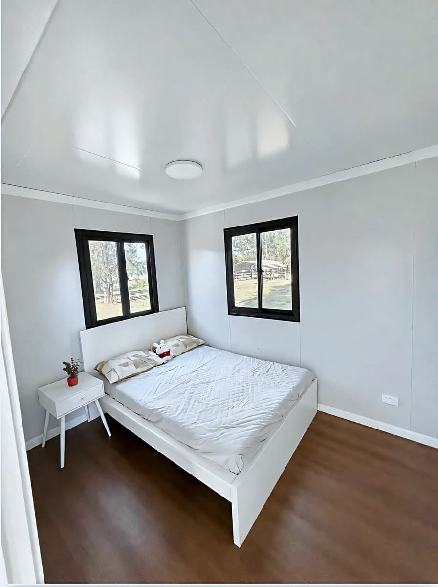 Bedroom with a double bed between two windows