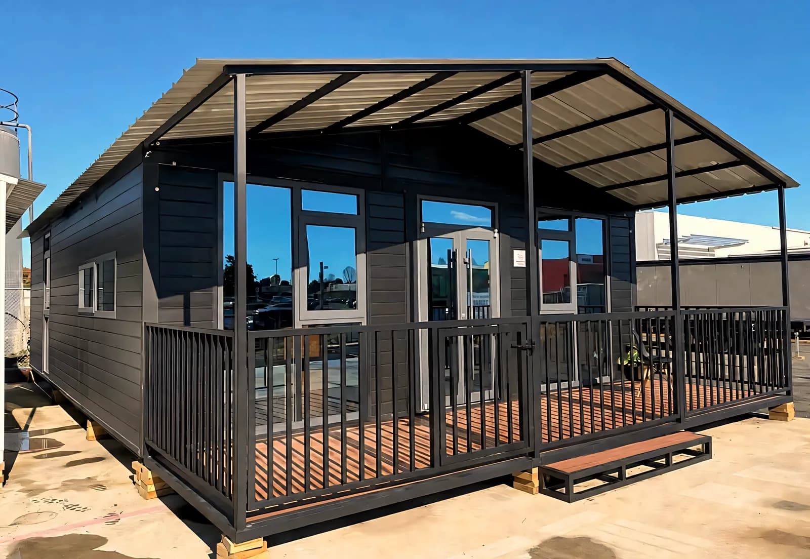 Black-clad cabin with a full-width veranda under a steel canopy