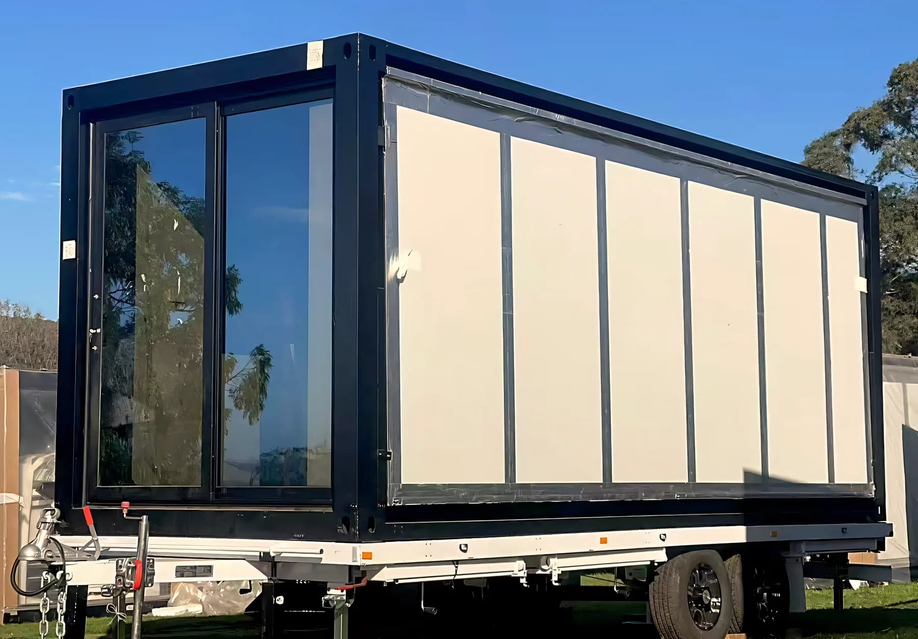 A compact unit mounted on a road trailer chassis, standing on grass