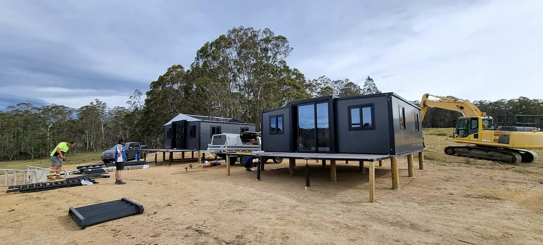 Two expandable units standing on timber piles on a cleared rural site
