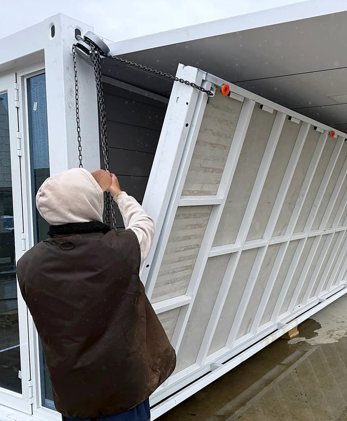 An installer lowering a wall panel on chains as a unit is unfolded