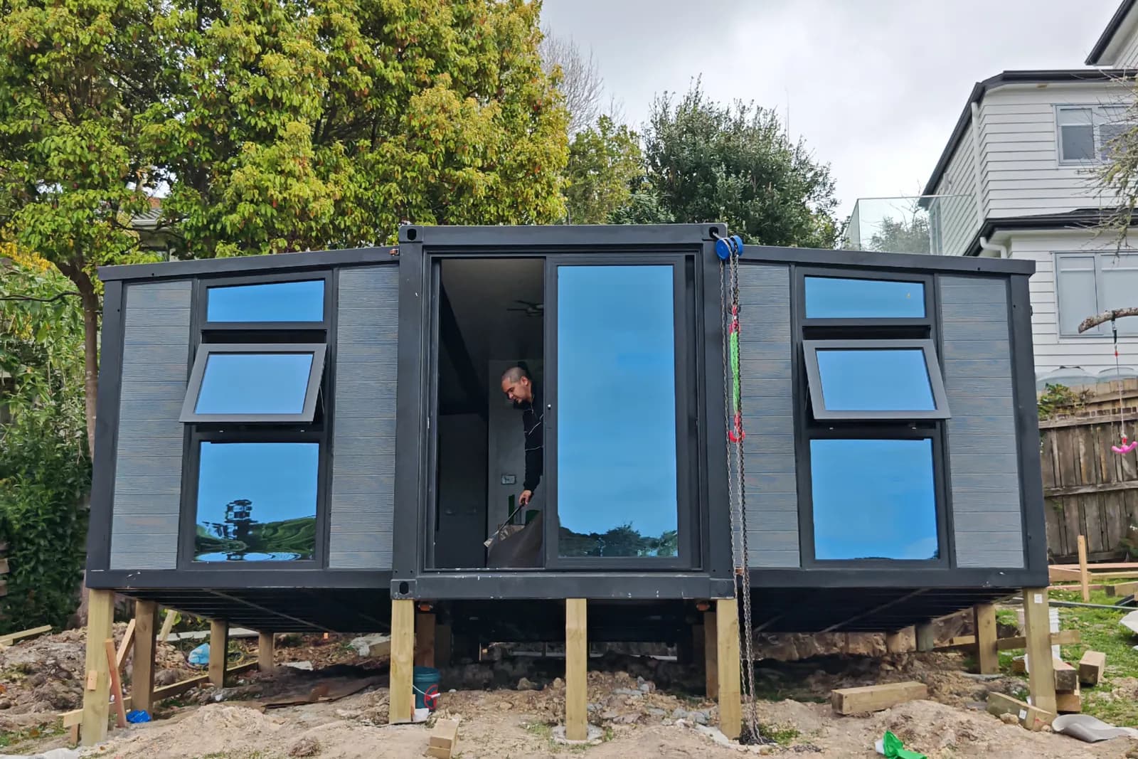 Comfort 20 with both wings unfolded, set on piles in a garden