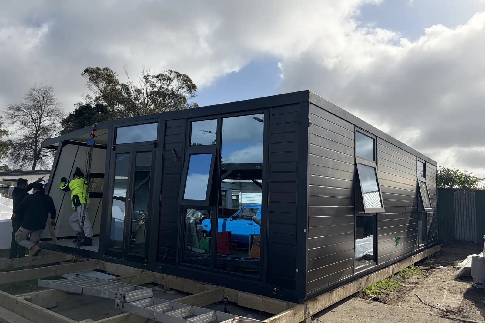 Install crew unfolding a black Comfort 30 on its timber subframe